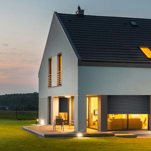 Panoramic photo of modern house with outdoor and indoor lighting, at night