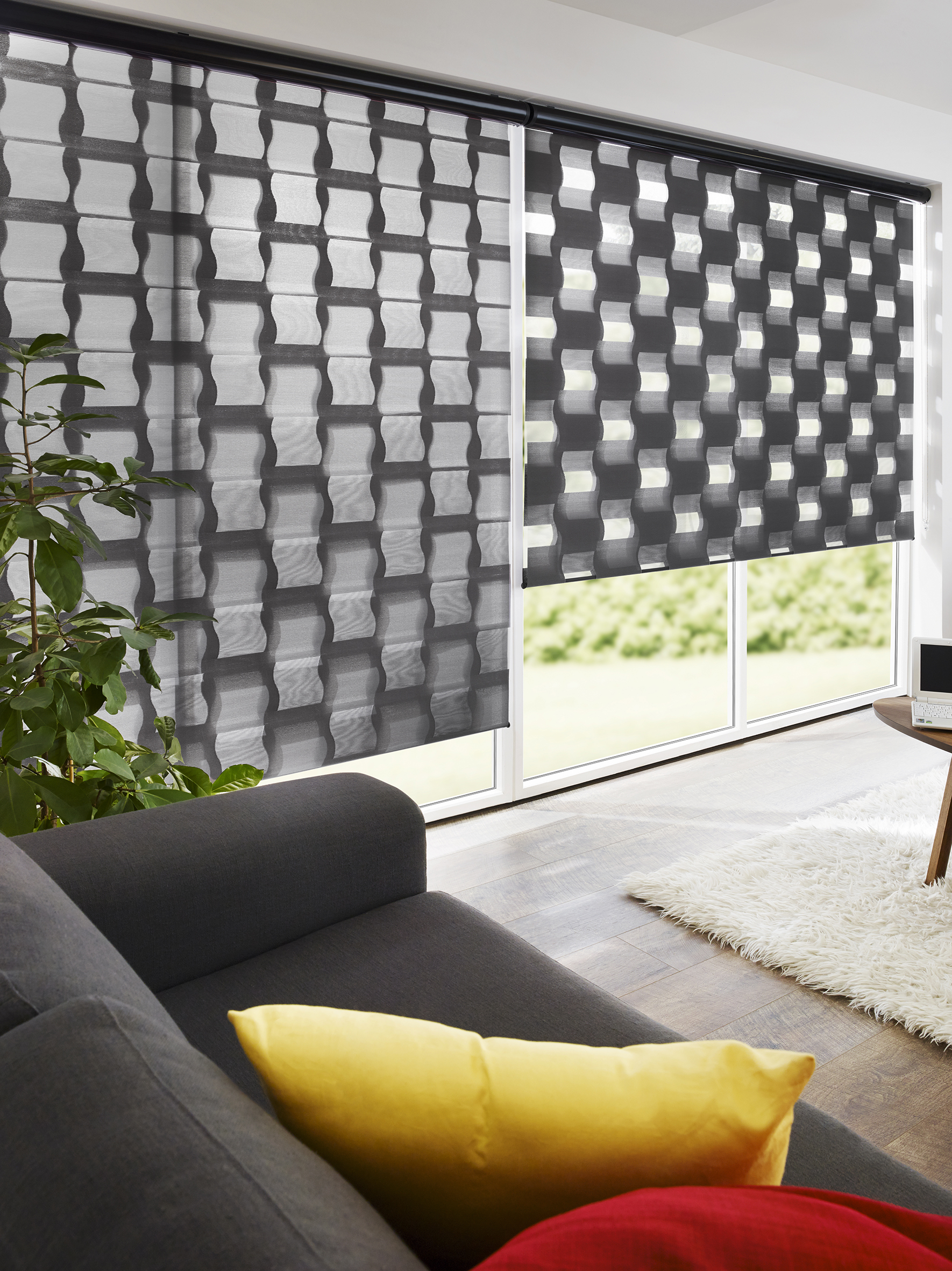 Helles Wohnzimmer mit Doppelrollo, Couch mit roten und gelben Kissen,  gelbe Wand und Teppich